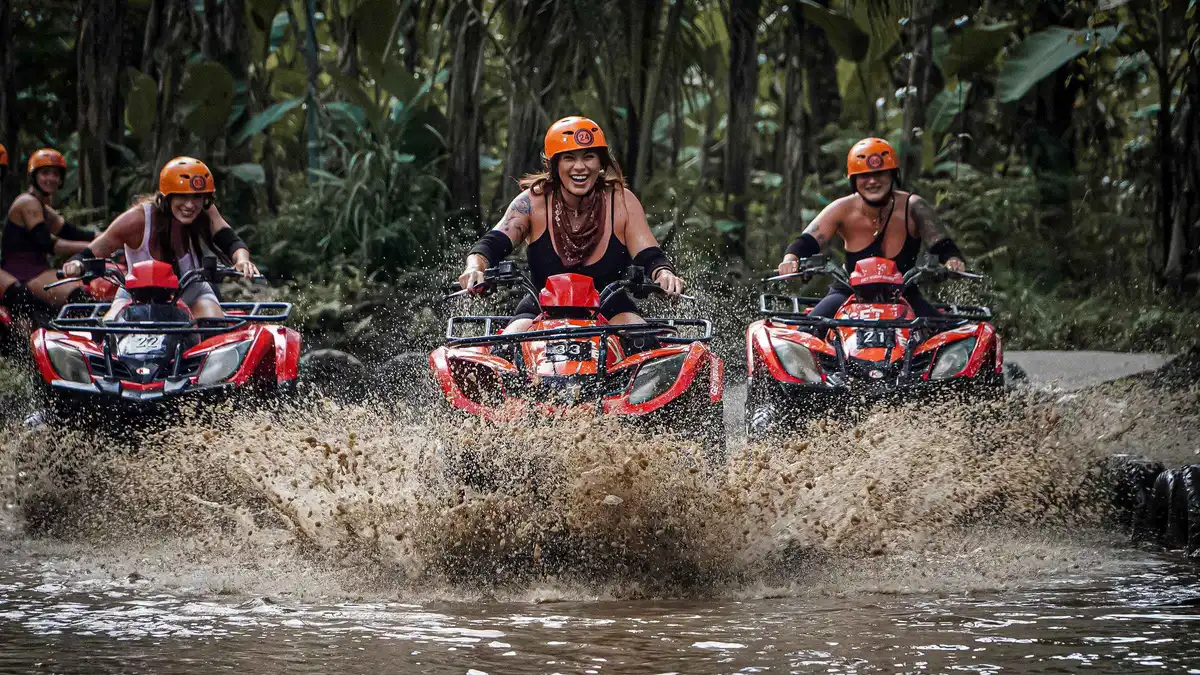 Riders on 250 cc quads splashing through a muddy jungle trail on a guided ATV tour in Ubud, Bali